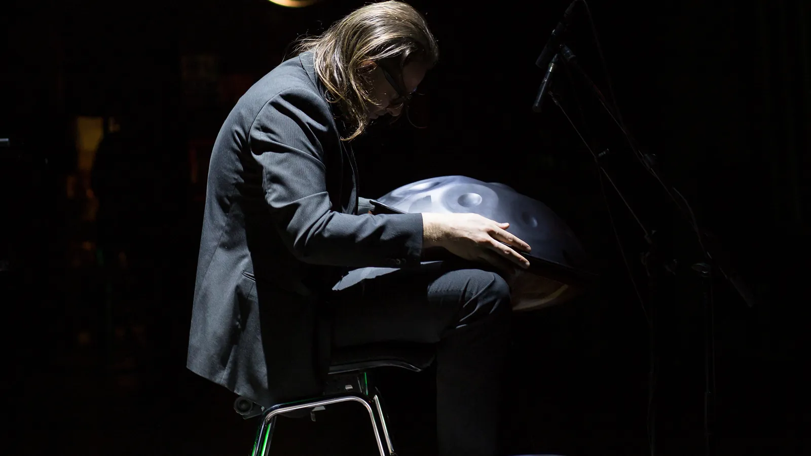Suonatore di handpan nella luce di scena, chino sullo strumento