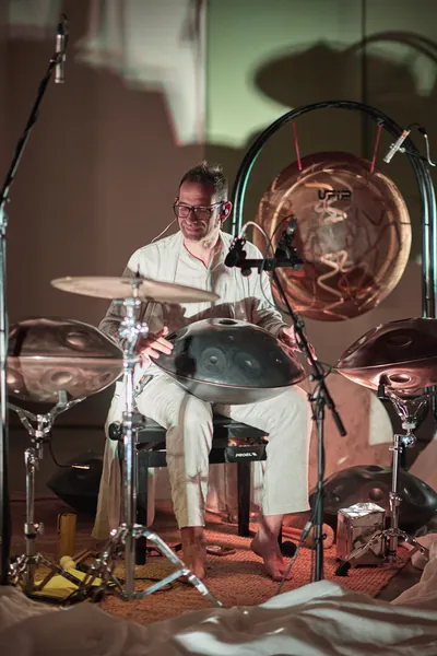 Musicista a piedi nudi tra handpan, gong e campane
