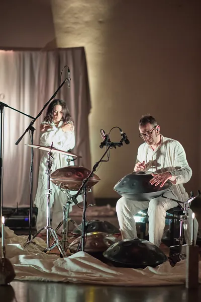 Canto e handpan tra teli bianchi e candele