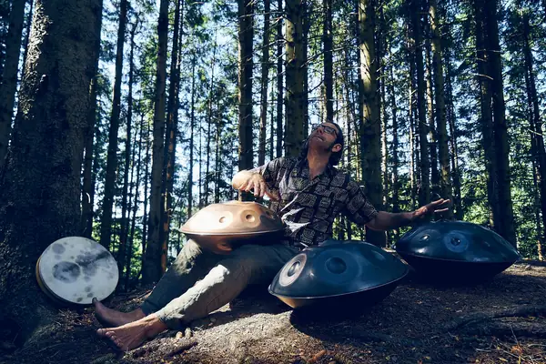 Suonatore di handpan a piedi nudi in una pineta
