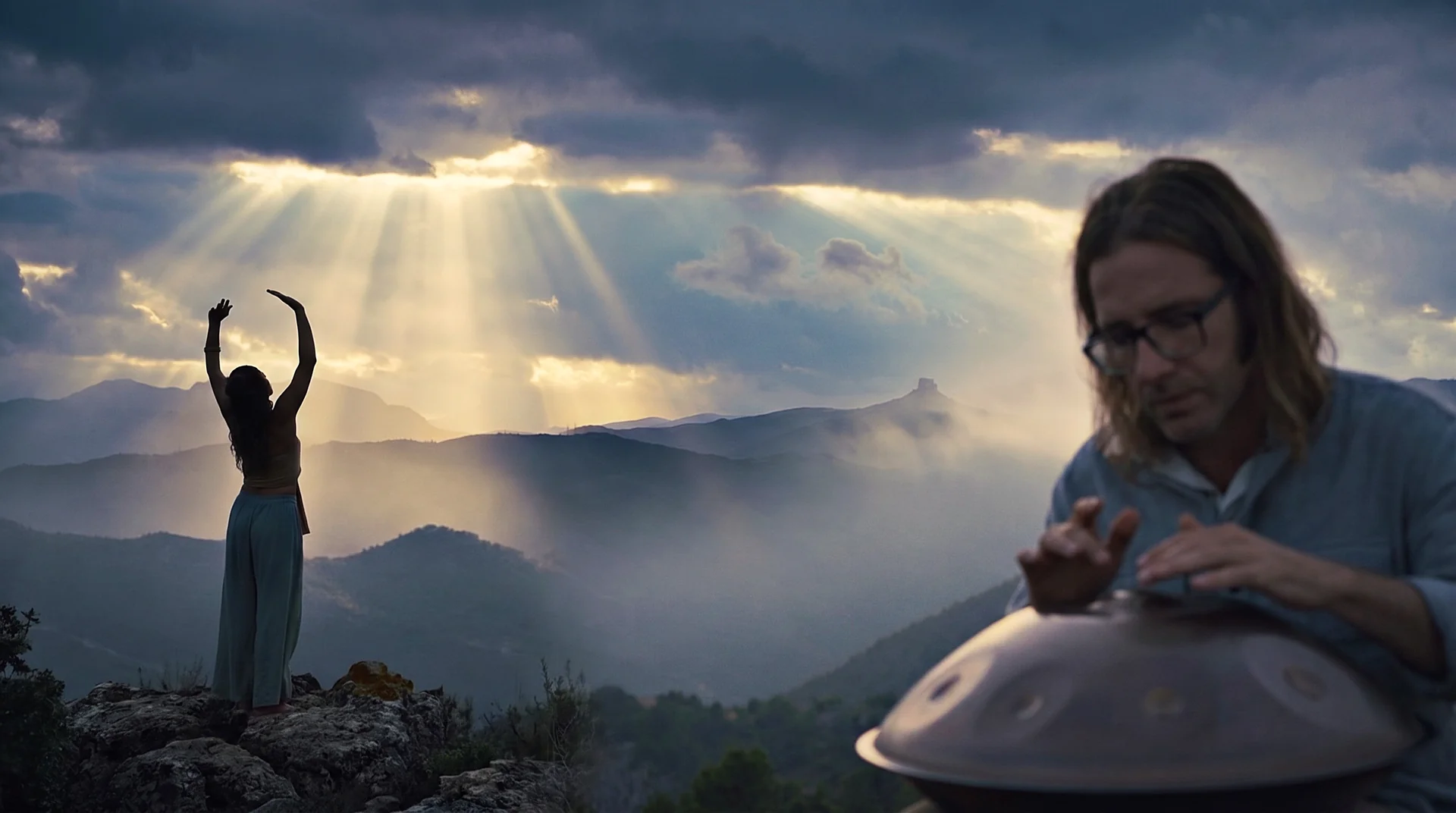 Handpan player and dancer on a mountain ridge at sunrise