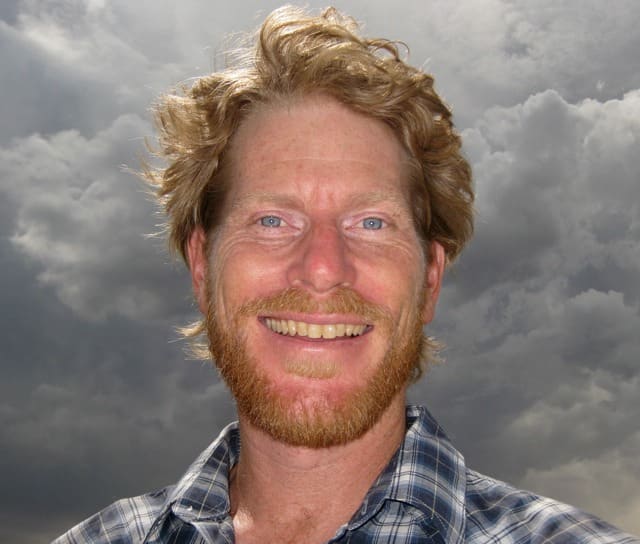 Head shot of Brad Lancaster in 2009, smiling, with a cloudy sky behind him.